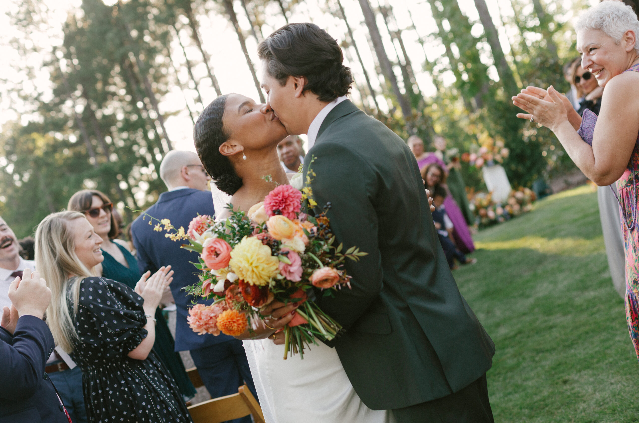 Couple kisses at end of ceremony aisle after marrying.